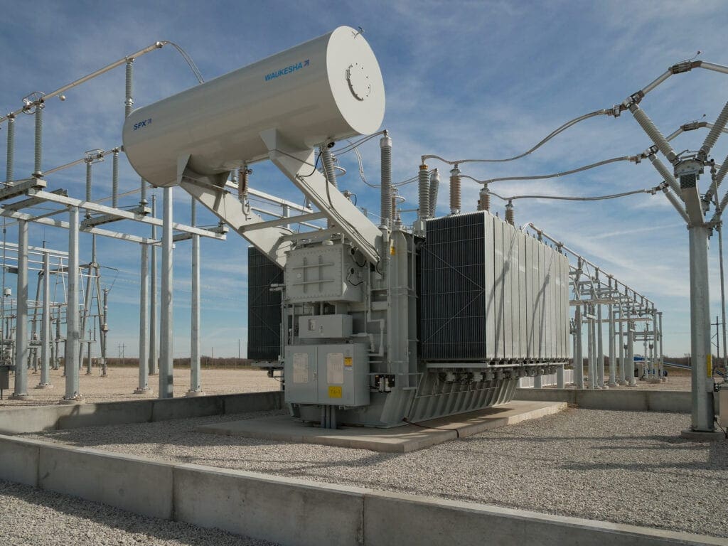 A large electrical power transformer on the side of a road.